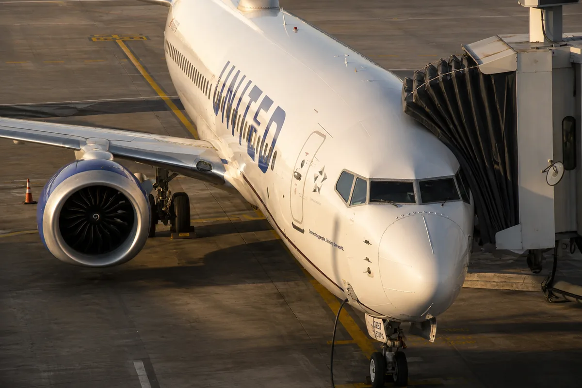 Single-aisle commercial aircraft connected to the boarding bridge on the apron